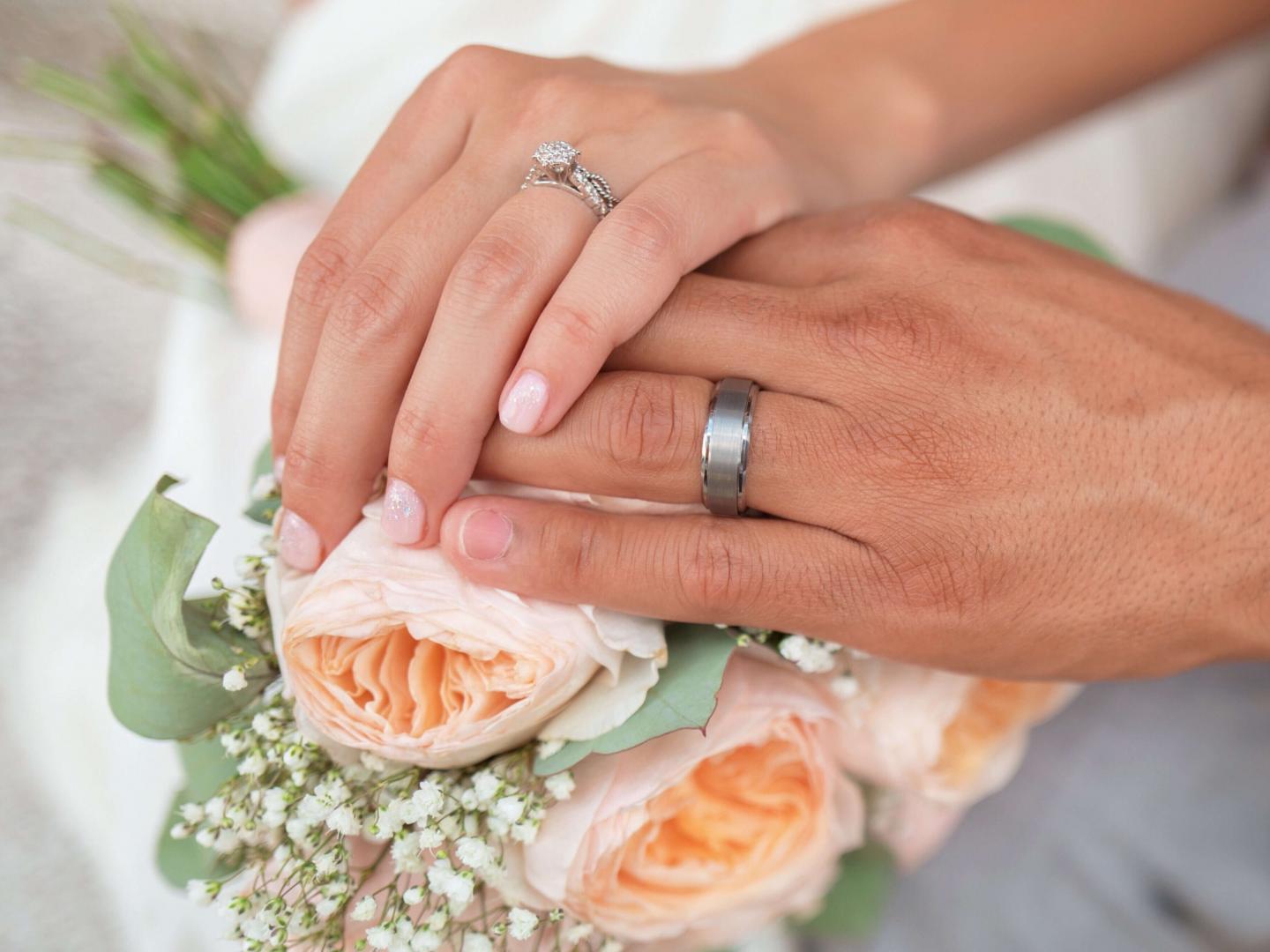 bride and groom hand sitting on top of flowers