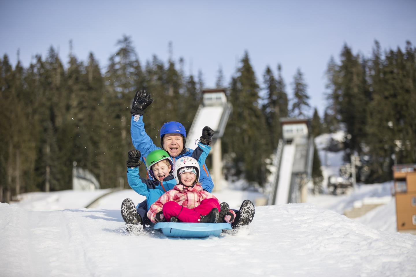 Family tobogganing in front of ski jump high res